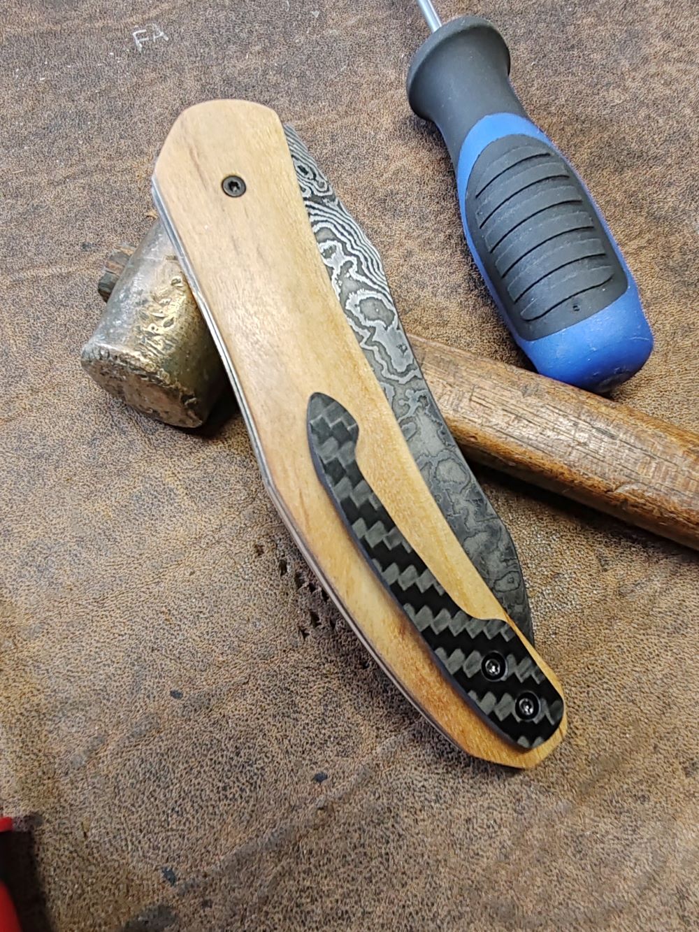 Couteau pliant artisanal avec lame en acier damas et manche en bois