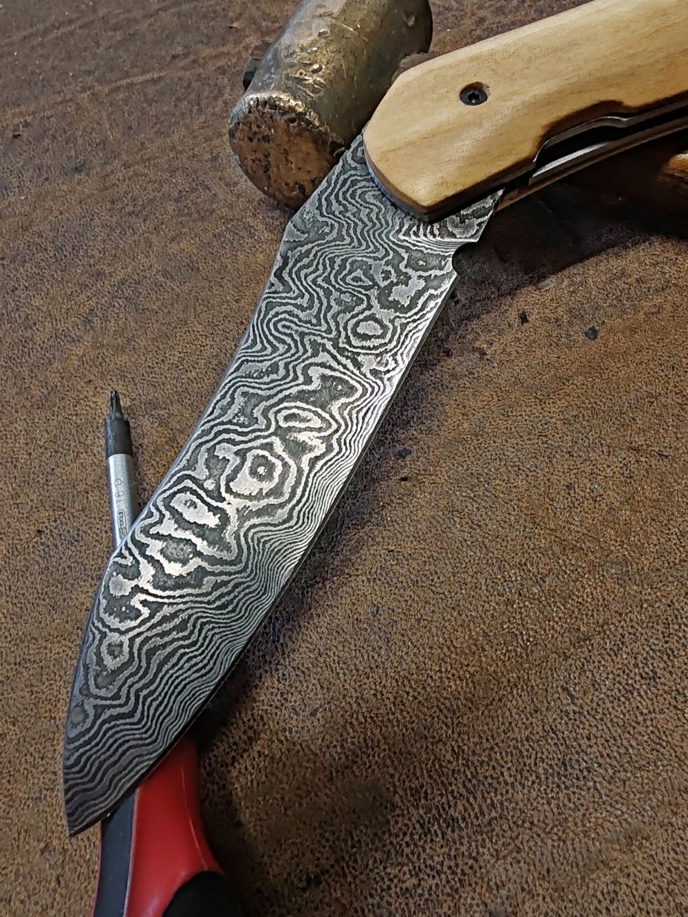 Couteau pliant artisanal avec lame en acier damas et manche en bois