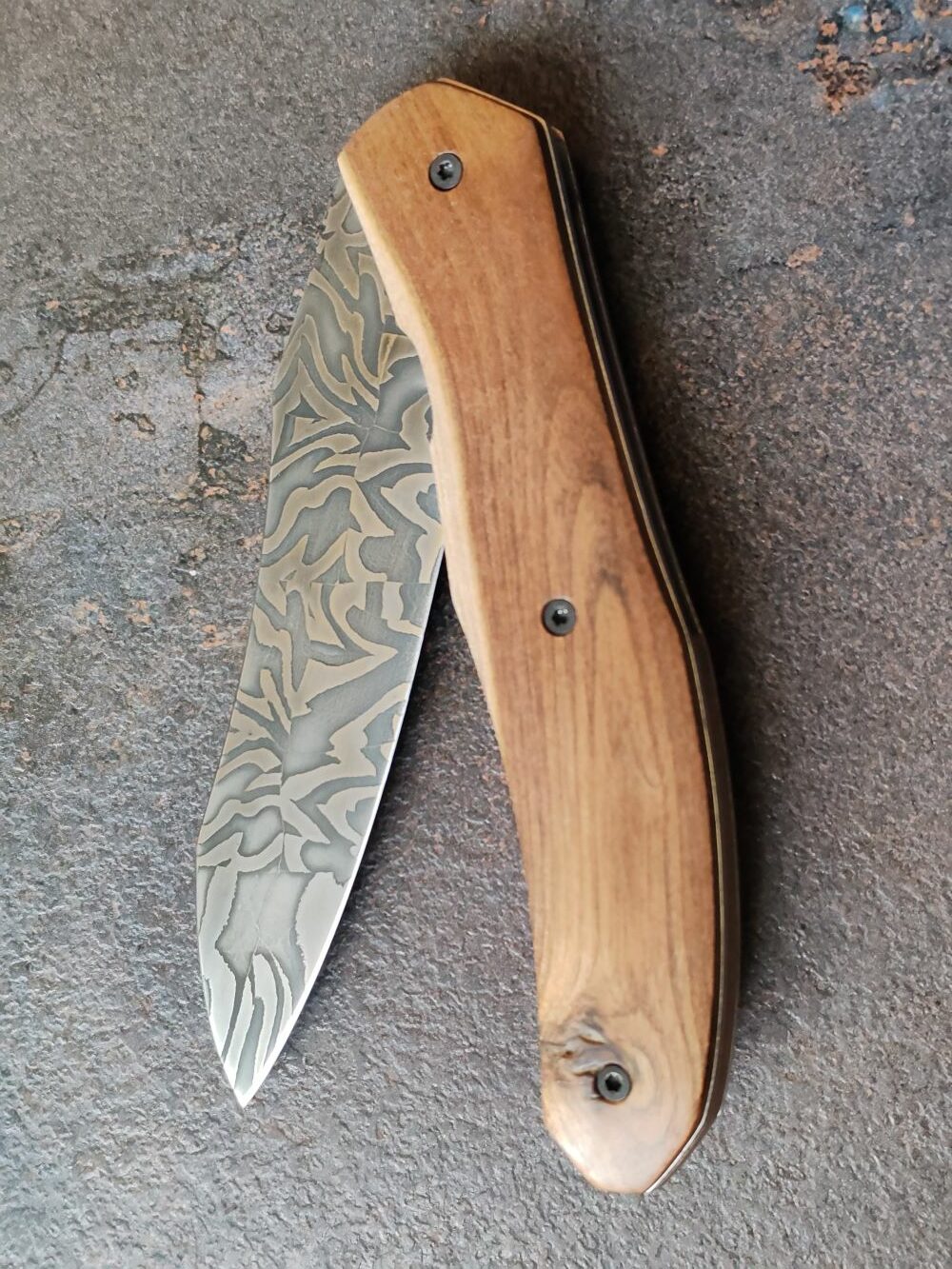 Couteau pliant artisanal avec lame en acier damas et manche en bois