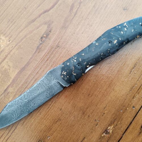 Couteau pliant artisanal avec lame en acier damas et manche en bois noir et or